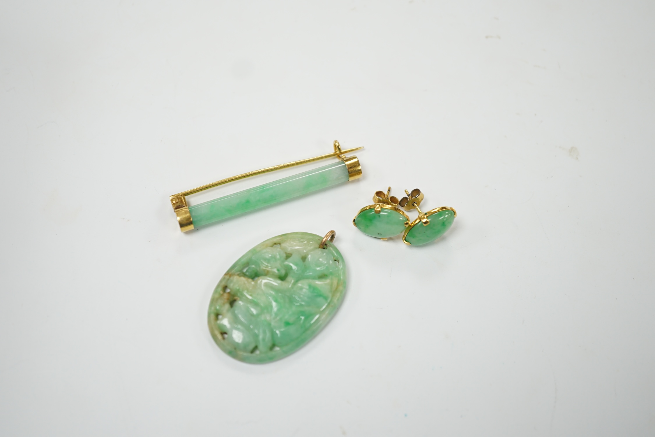 A Chinese yellow metal(stamped 18) mounted jade bar brooch, 48mm, a carved jade pendant and a pair of yellow metal mounted oval jade earrings, gross weight 19.9 grams. Fair to good condition.